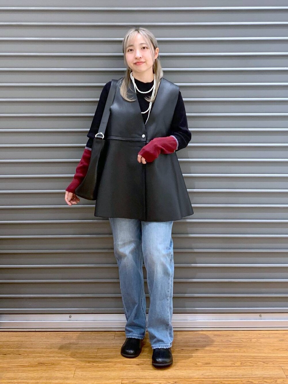 ブルー系のデニムパンツ、ブラック系のニット/セーター、ブラック系のショルダーバッグを着用したレディースの秋コーディネートの5枚目の写真