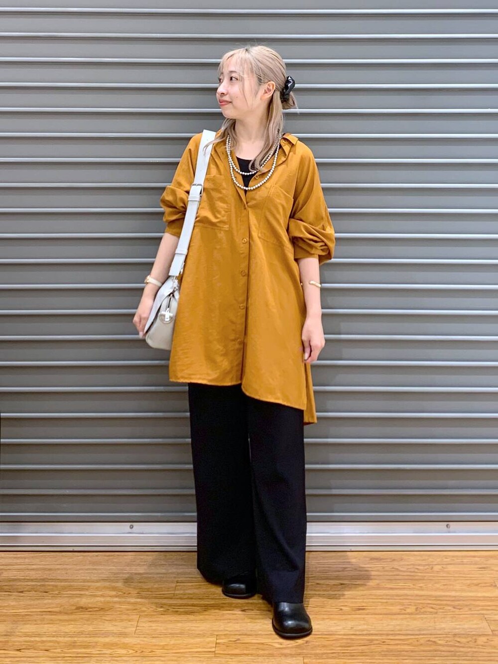 オレンジ系のシャツ/ブラウス、ブラック系のその他パンツ、グレー系のショルダーバッグを着用したレディースの秋コーディネートの4枚目の写真