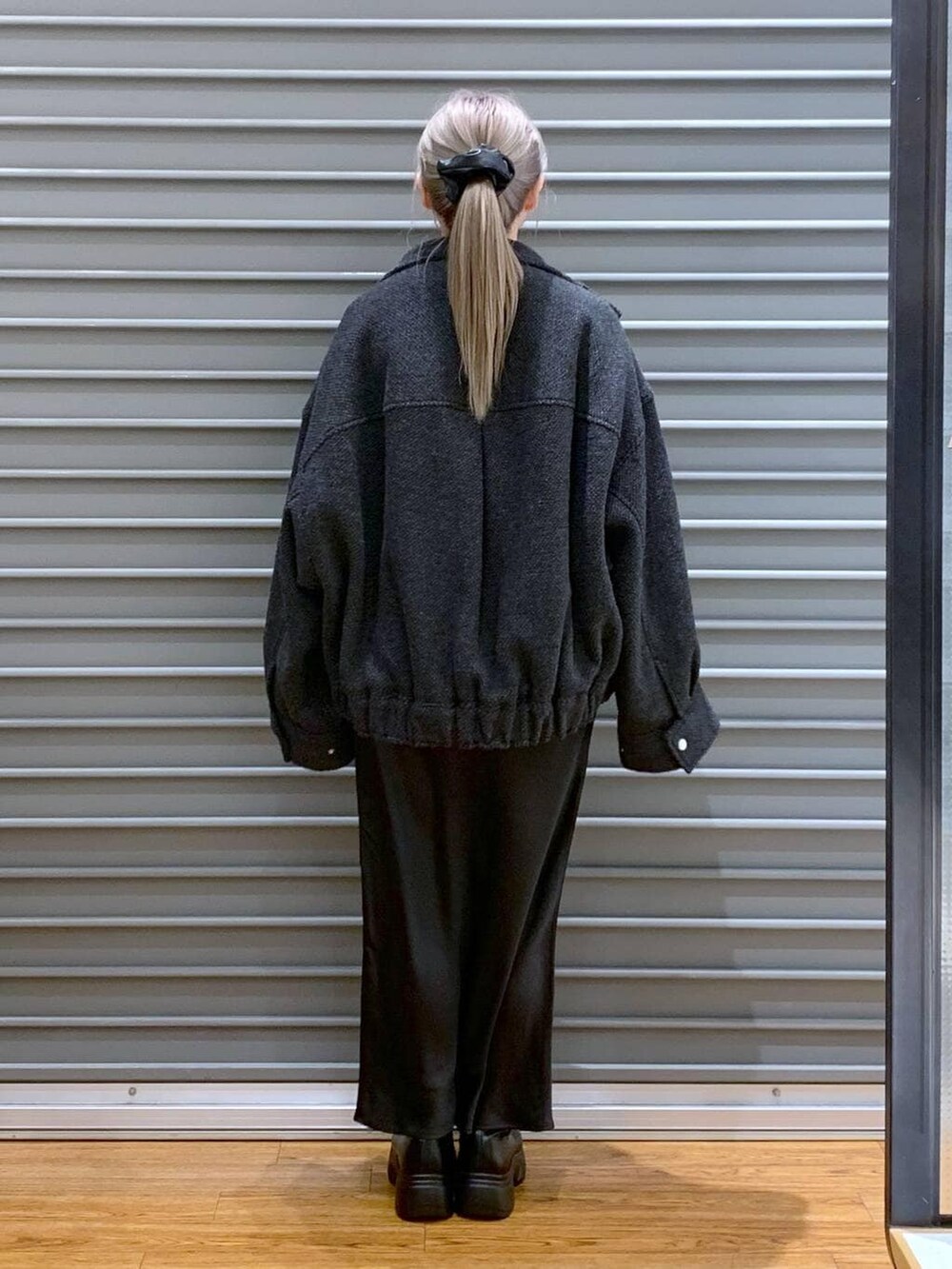 ブラック系のスカート、グリーン系のショルダーバッグ、ブラック系のブルゾンを着用したレディースの冬コーディネートの2枚目の写真