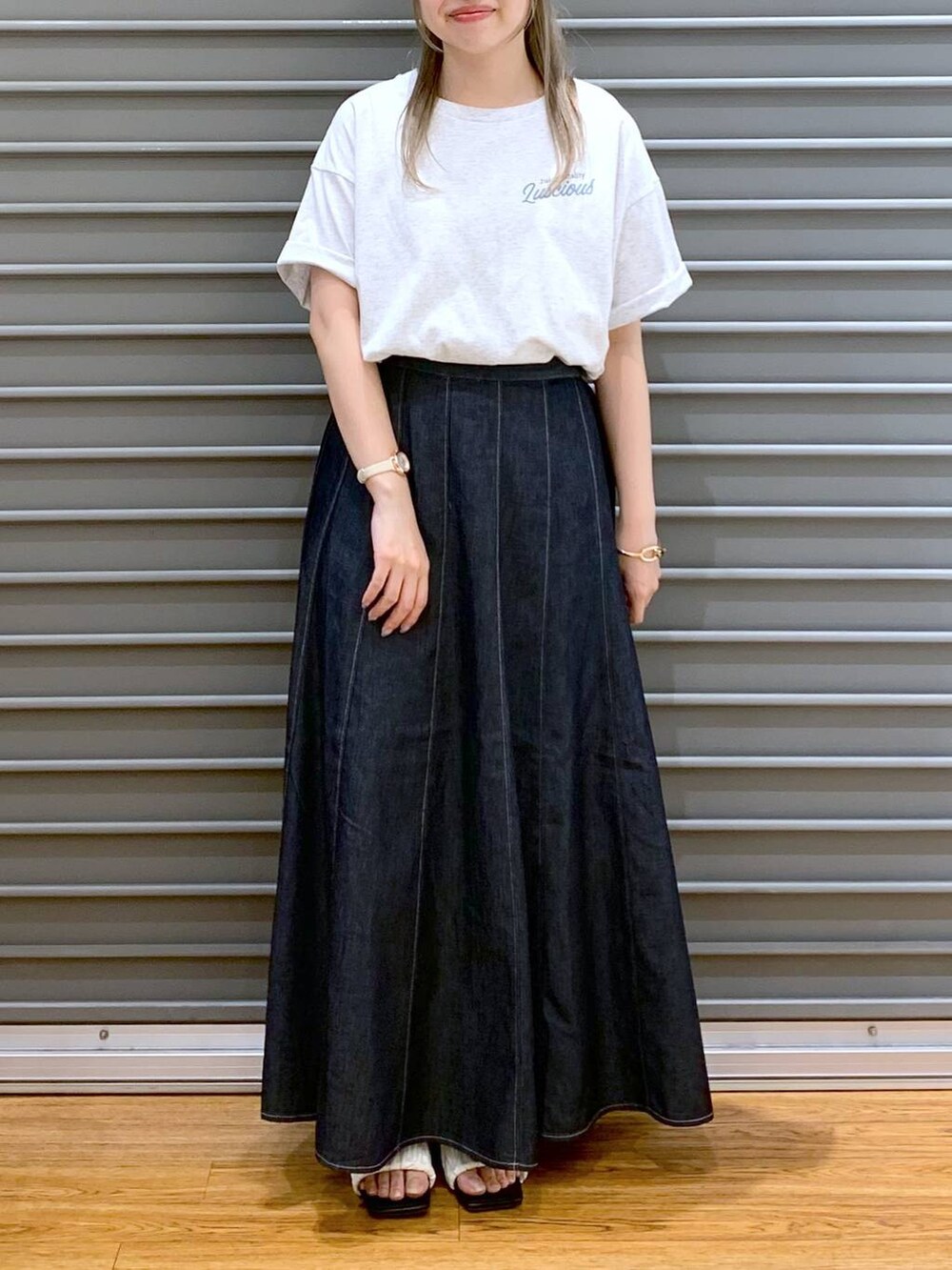 ブルー系のスカート、ホワイト系のサンダル、ブラック系のショルダーバッグを着用したレディースの夏コーディネートの6枚目の写真