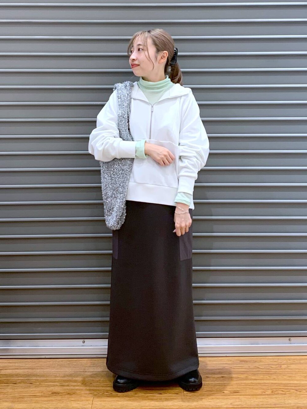 ブラック系のブーツ、シルバー系のショルダーバッグ、グレー系のスカートを着用したレディースの冬コーディネートの4枚目の写真