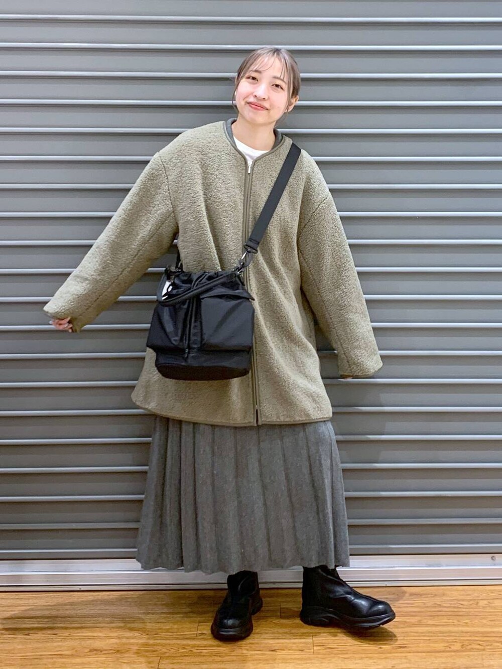 ブラック系のショルダーバッグ、グリーン系のその他アウター、ブラック系のブーツを着用したレディースの冬コーディネートの7枚目の写真