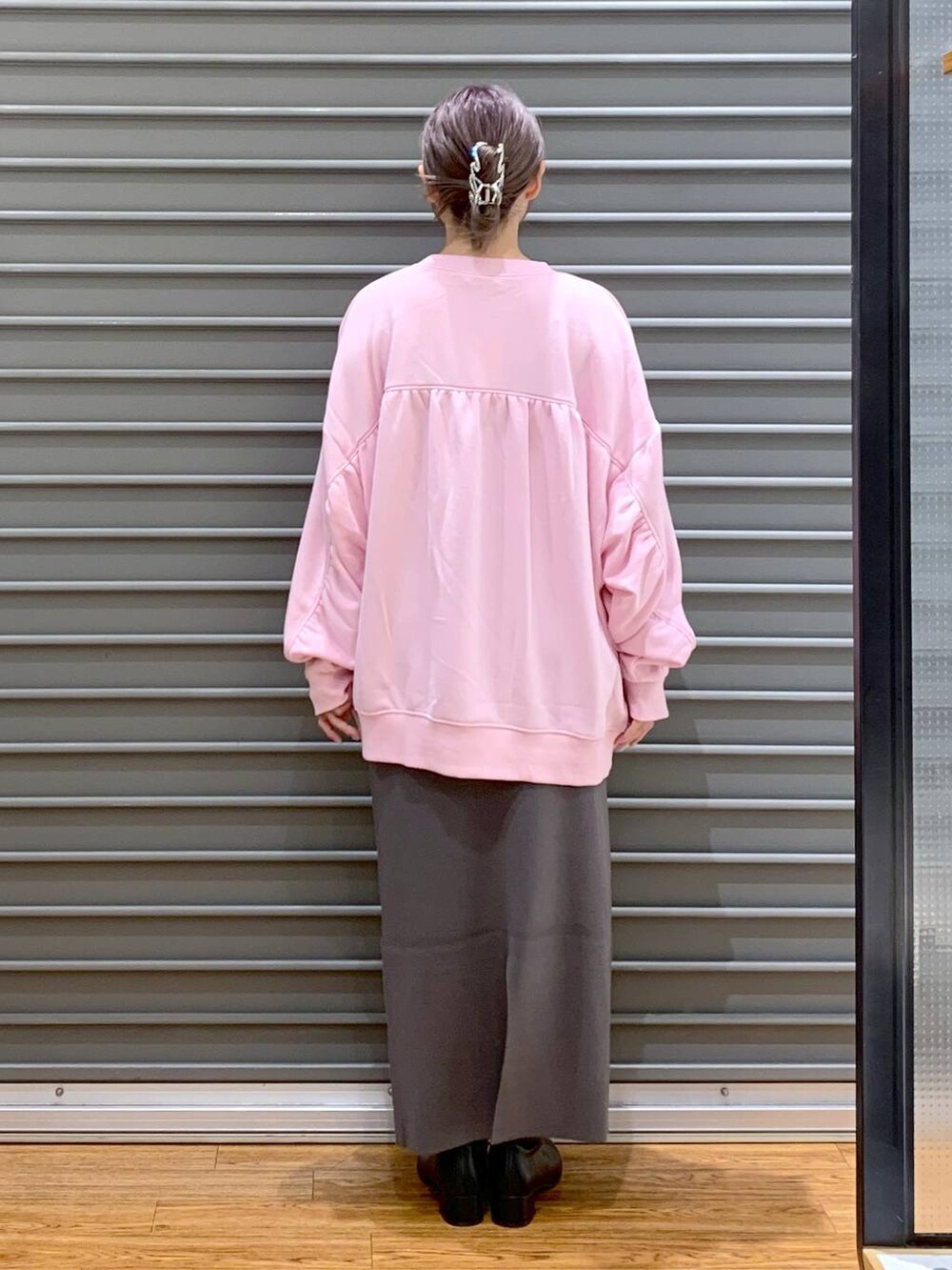 グレー系のスカート、ブラック系のブーツ、ピンク系のスウェットを着用したレディースの冬コーディネートの2枚目の写真