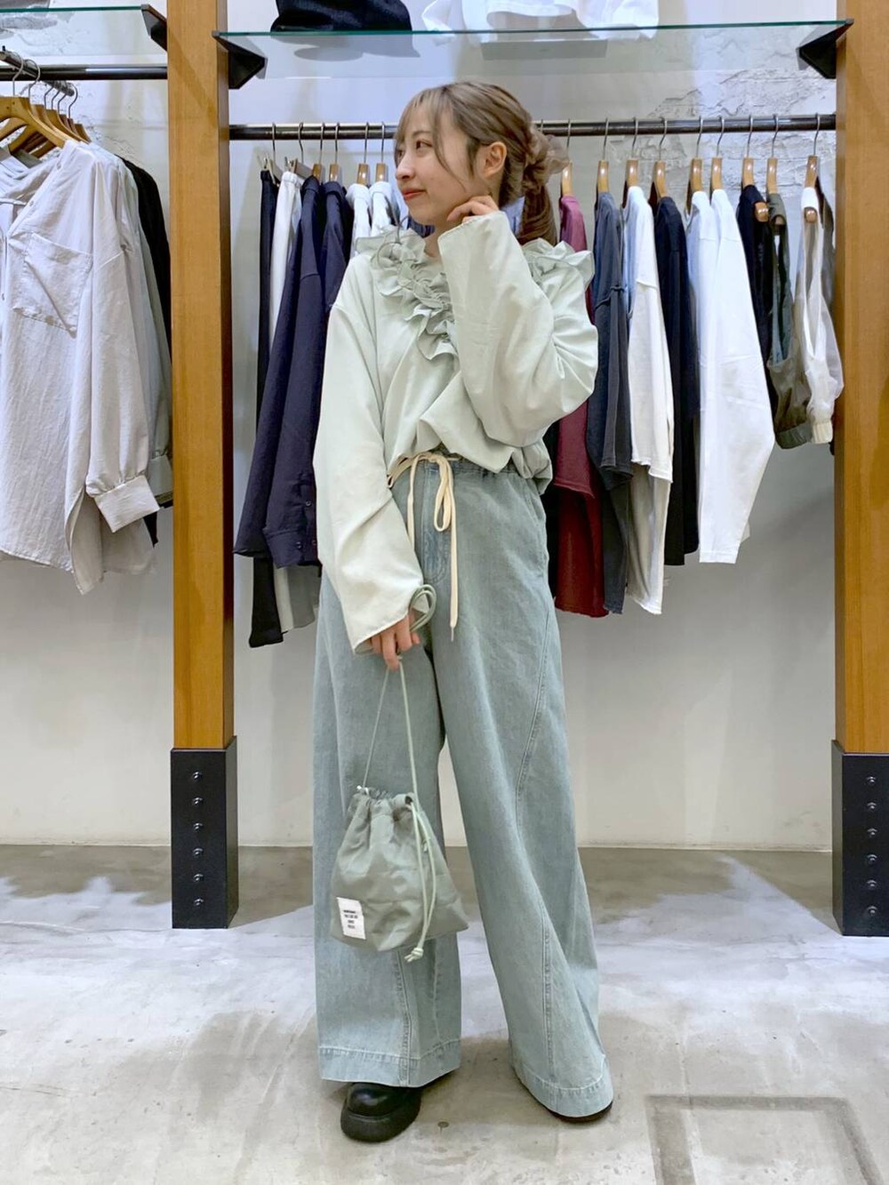 グリーン系のショルダーバッグ、ブルー系のデニムパンツ、ブラック系のサンダルを着用したレディースの春コーディネートの6枚目の写真