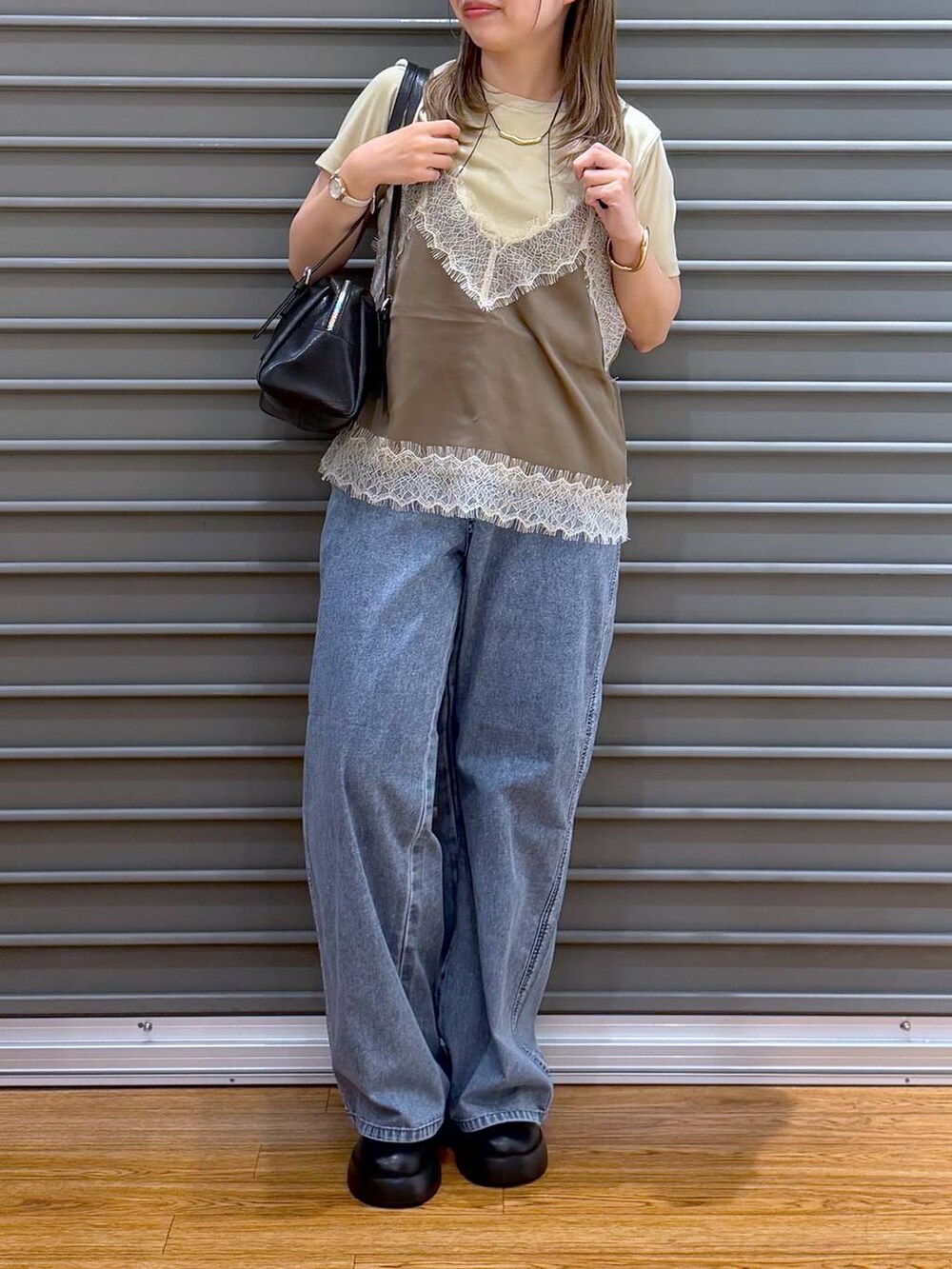 ブラック系のサンダル、ブラック系のボストンバッグ、ブルー系のデニムパンツを着用したレディースの春コーディネートの4枚目の写真