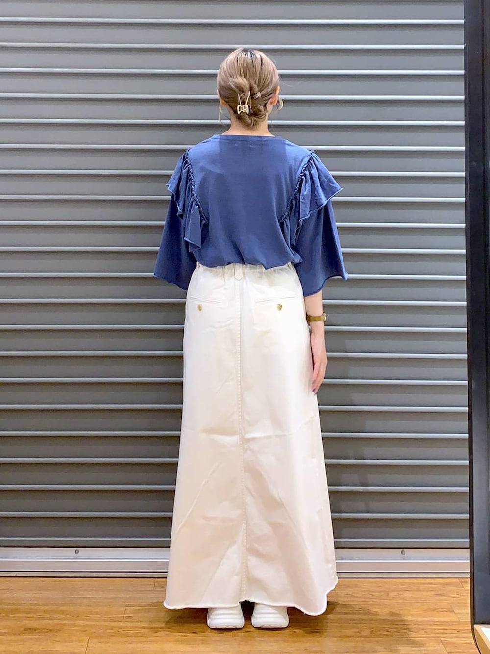 ホワイト系のスカート、ホワイト系のスニーカー、シルバー系のボストンバッグを着用したレディースの夏コーディネートの2枚目の写真