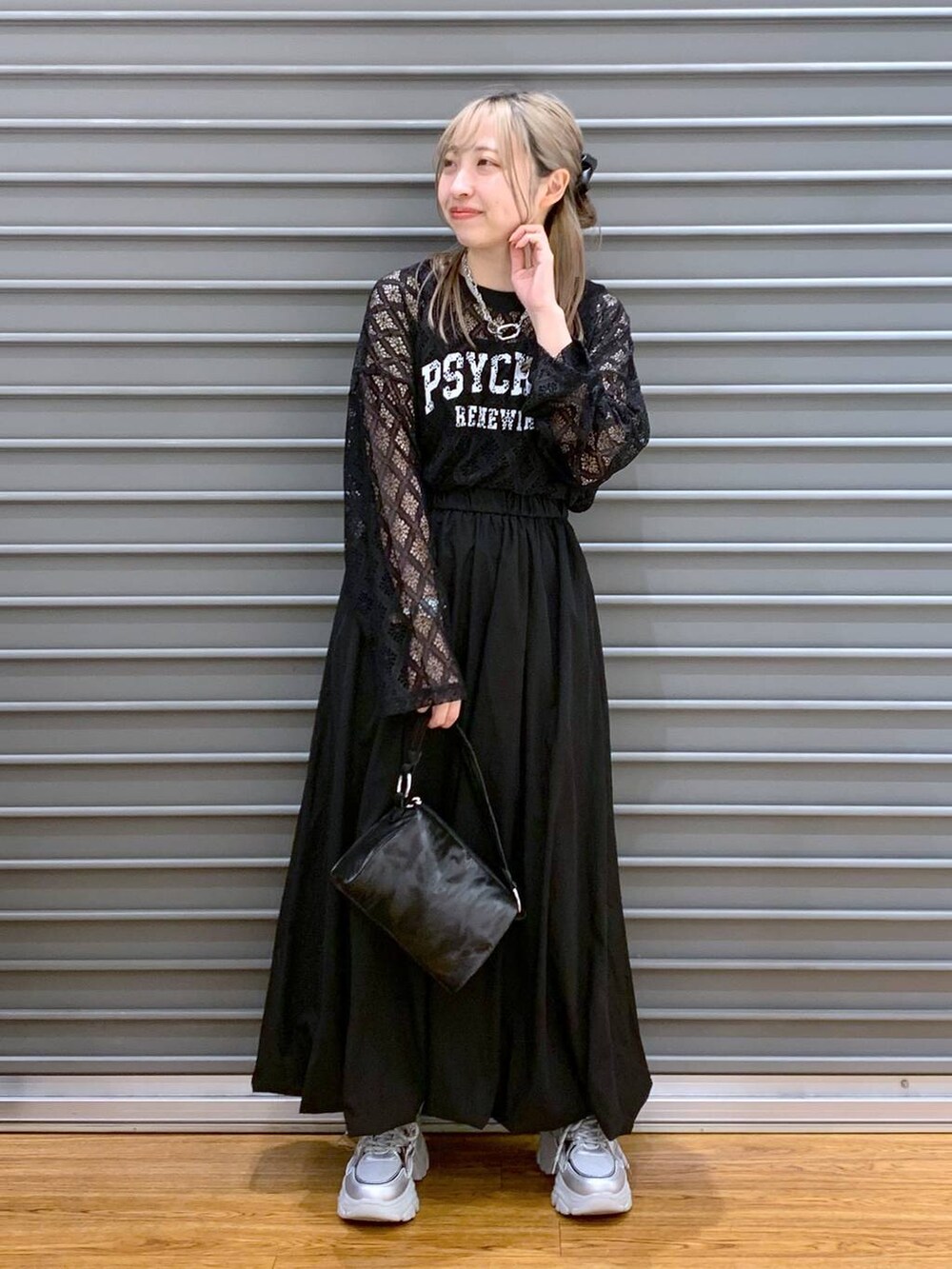 シルバー系のスニーカー、ブラック系のスカート、ブラック系のハンドバッグを着用したレディースの春コーディネートの4枚目の写真