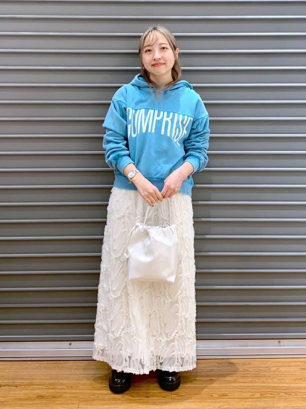 ブルー系のパーカー、ホワイト系のスカート、ブラック系のローファーを着用したレディースの冬コーディネートの4枚目の写真