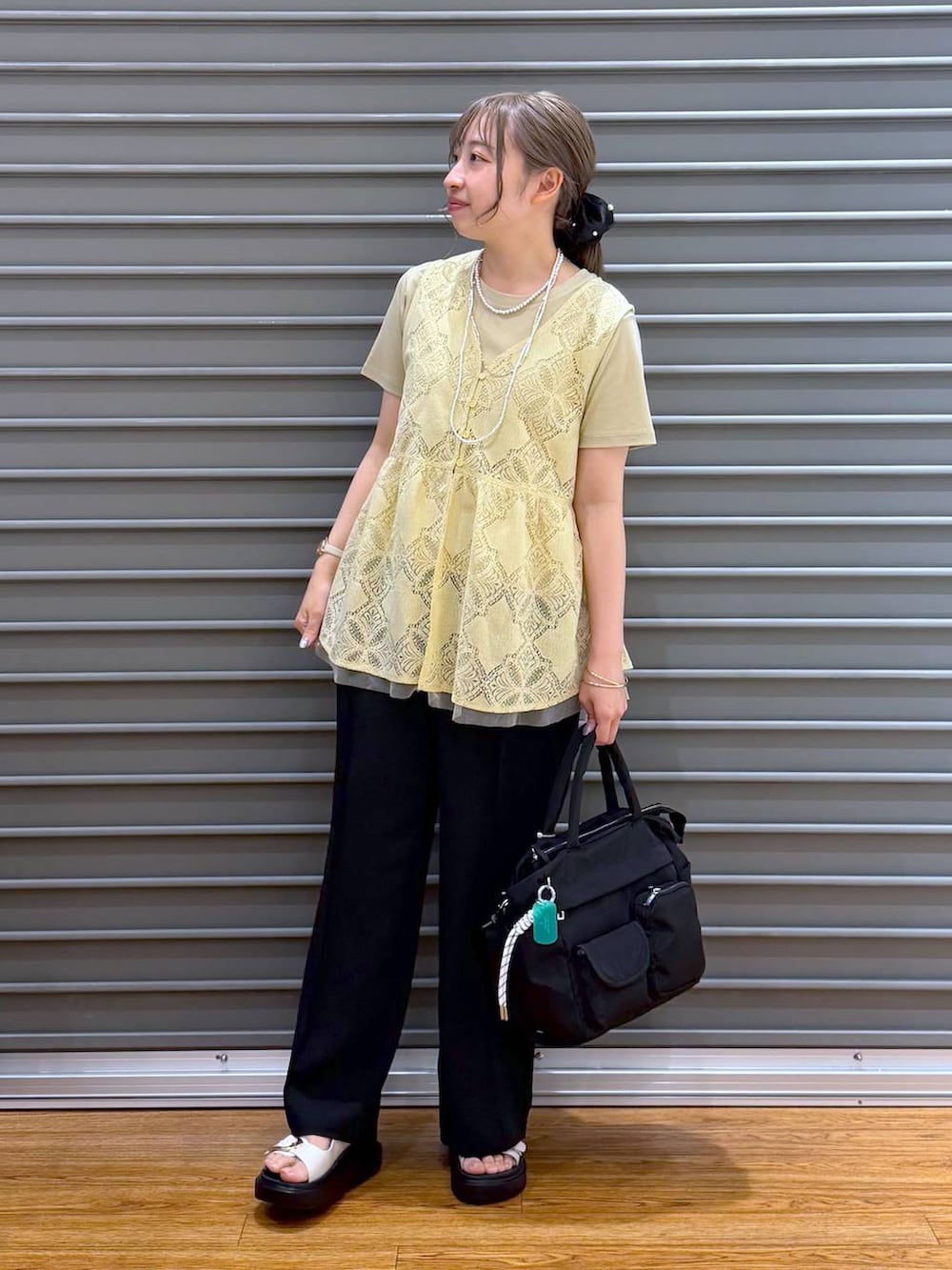 ブラック系のトートバッグ、ホワイト系のサンダル、ベージュ系のTシャツ/カットソーを着用したレディースの夏コーディネートの6枚目の写真