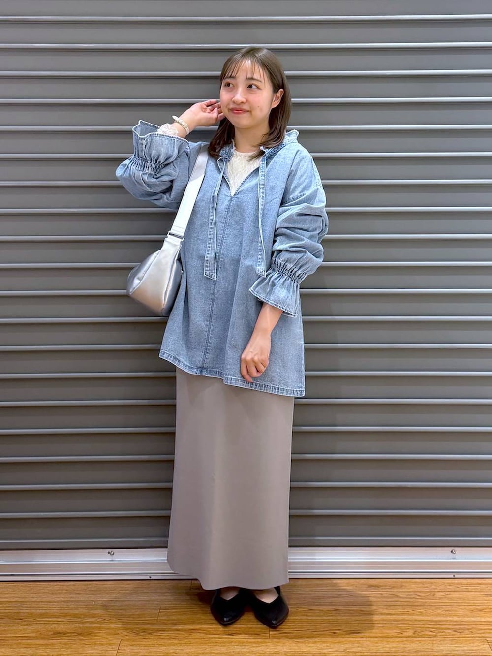 グレー系のスカート、ブラック系のパンプス、シルバー系のショルダーバッグを着用したレディースの春コーディネートの4枚目の写真