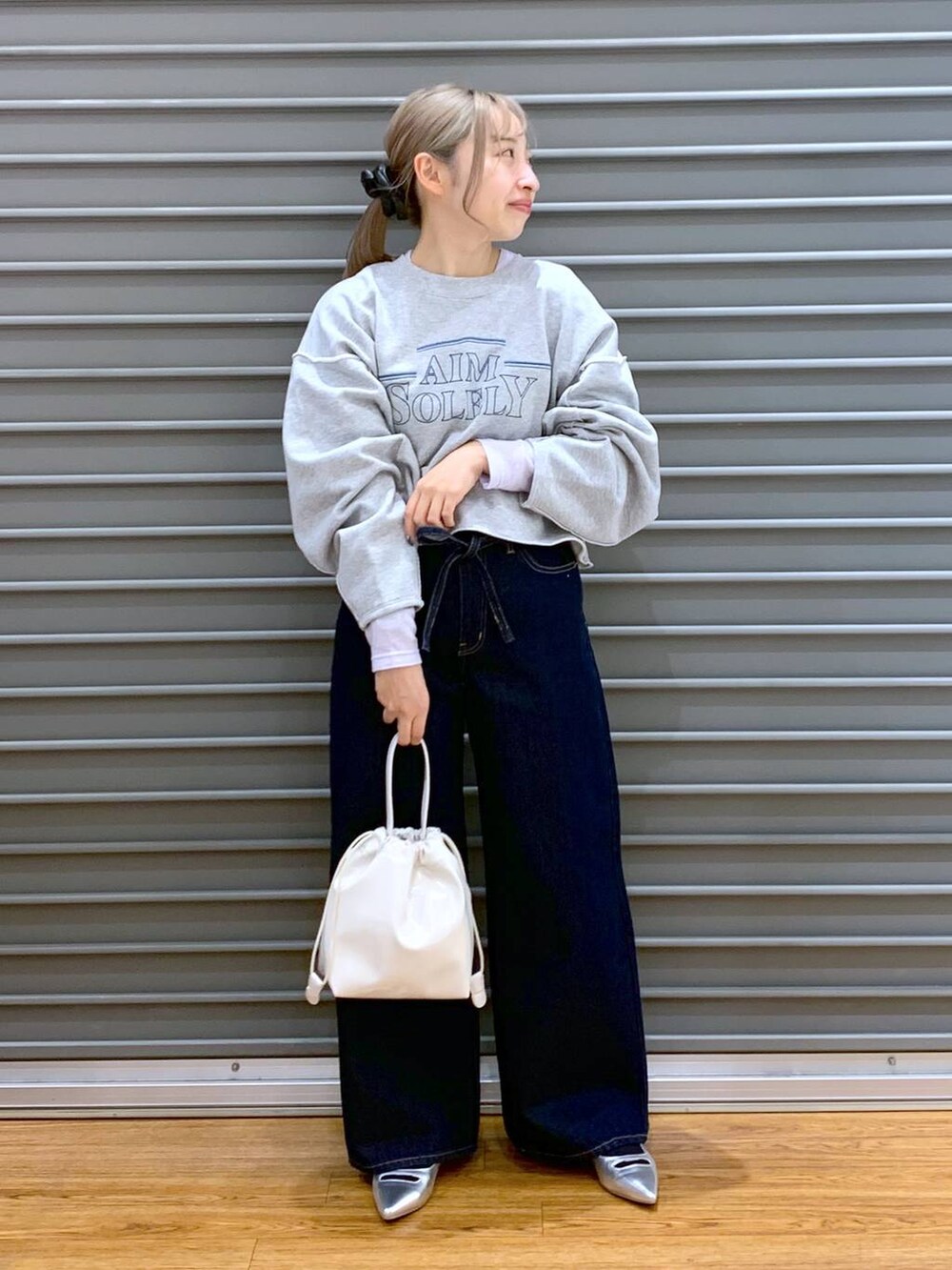 パープル系のTシャツ/カットソー、ブルー系のデニムパンツ、シルバー系のパンプスを着用したレディースの冬コーディネートの6枚目の写真