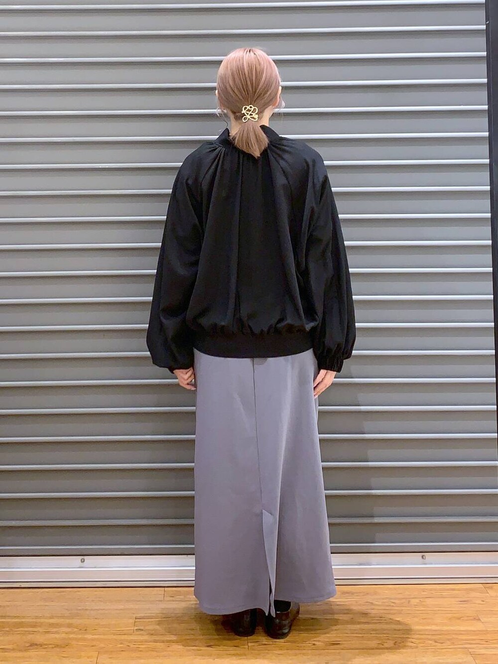 ブラック系のショルダーバッグ、ブラック系のパンプス、グレー系のスカートを着用したレディースの春コーディネートの2枚目の写真