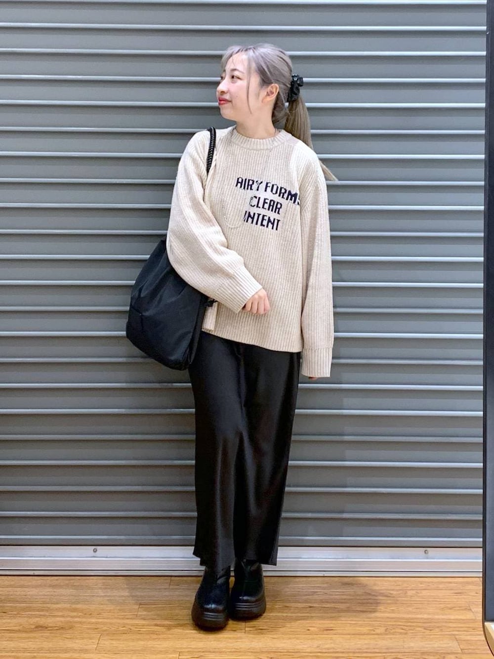 ブラック系のスカート、ブラック系のブーツ、ブラック系のトートバッグを着用したレディースの冬コーディネートの6枚目の写真