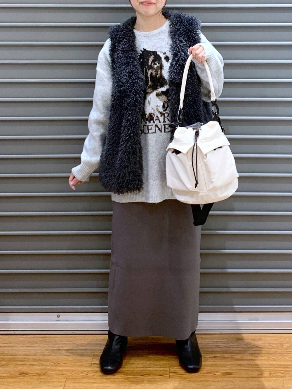 ホワイト系のショルダーバッグ、グレー系のスカート、ブラック系のブーツを着用したレディースの冬コーディネートの3枚目の写真