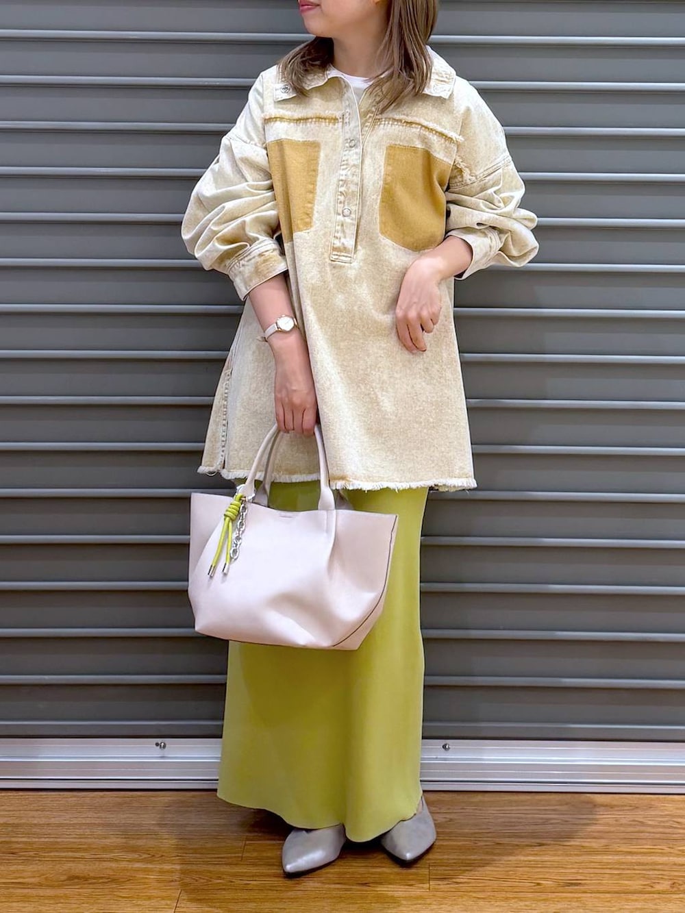 グリーン系のスカート、シルバー系のパンプス、ホワイト系のトートバッグを着用したレディースの春コーディネートの4枚目の写真