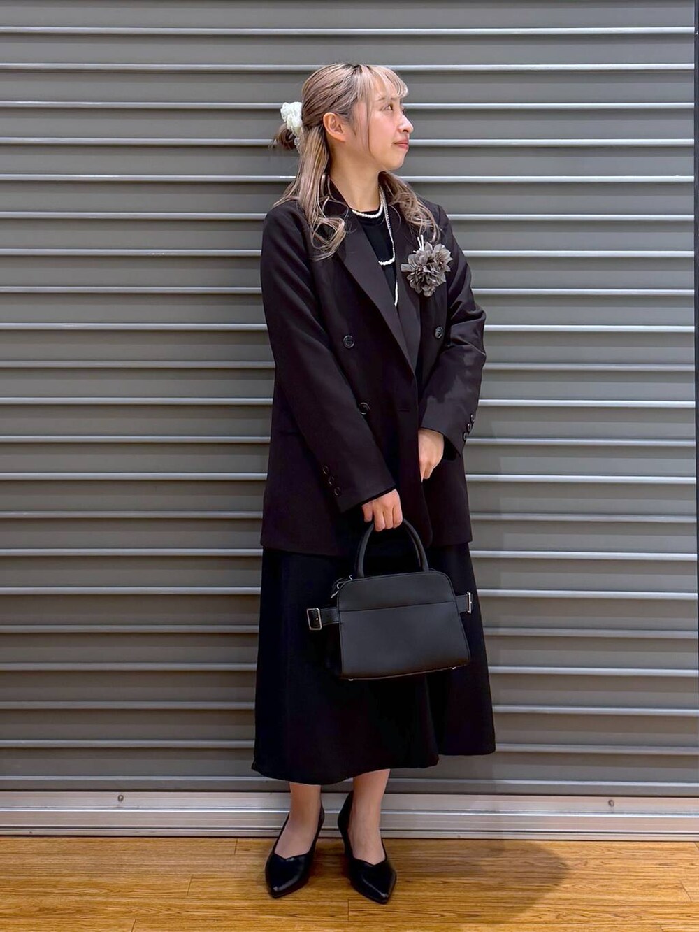 ブラック系のテーラードジャケット、ブラック系のワンピース、ブラック系のショルダーバッグを着用したレディースの冬コーディネートの6枚目の写真