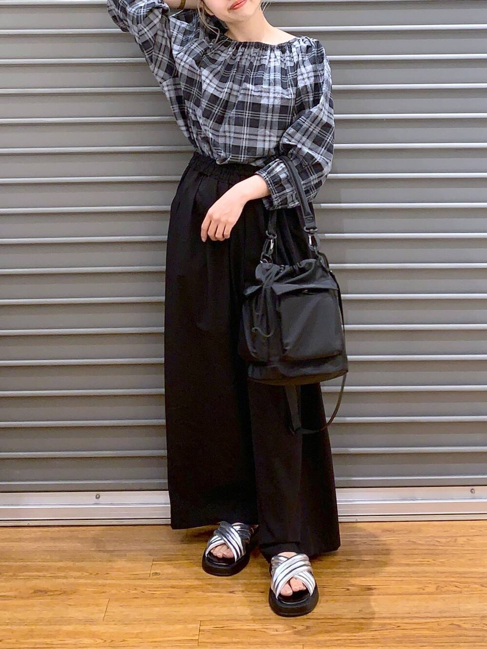 ブラック系のショルダーバッグ、シルバー系のサンダル、ブラック系のスラックスを着用したレディースの夏コーディネートの6枚目の写真