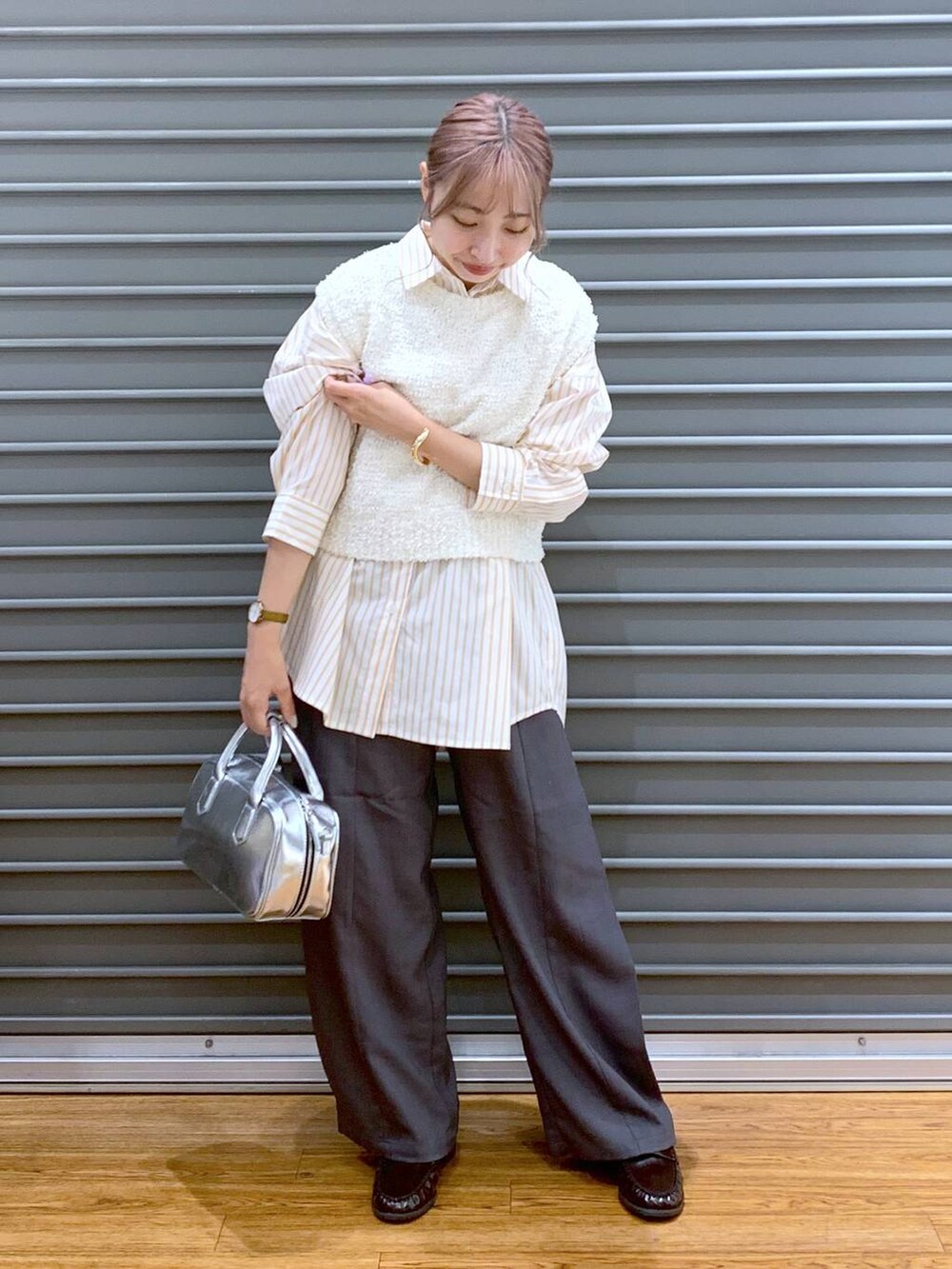 シルバー系のボストンバッグ、ホワイト系のベスト、オレンジ系のシャツ/ブラウスを着用したレディースの秋コーディネートの6枚目の写真