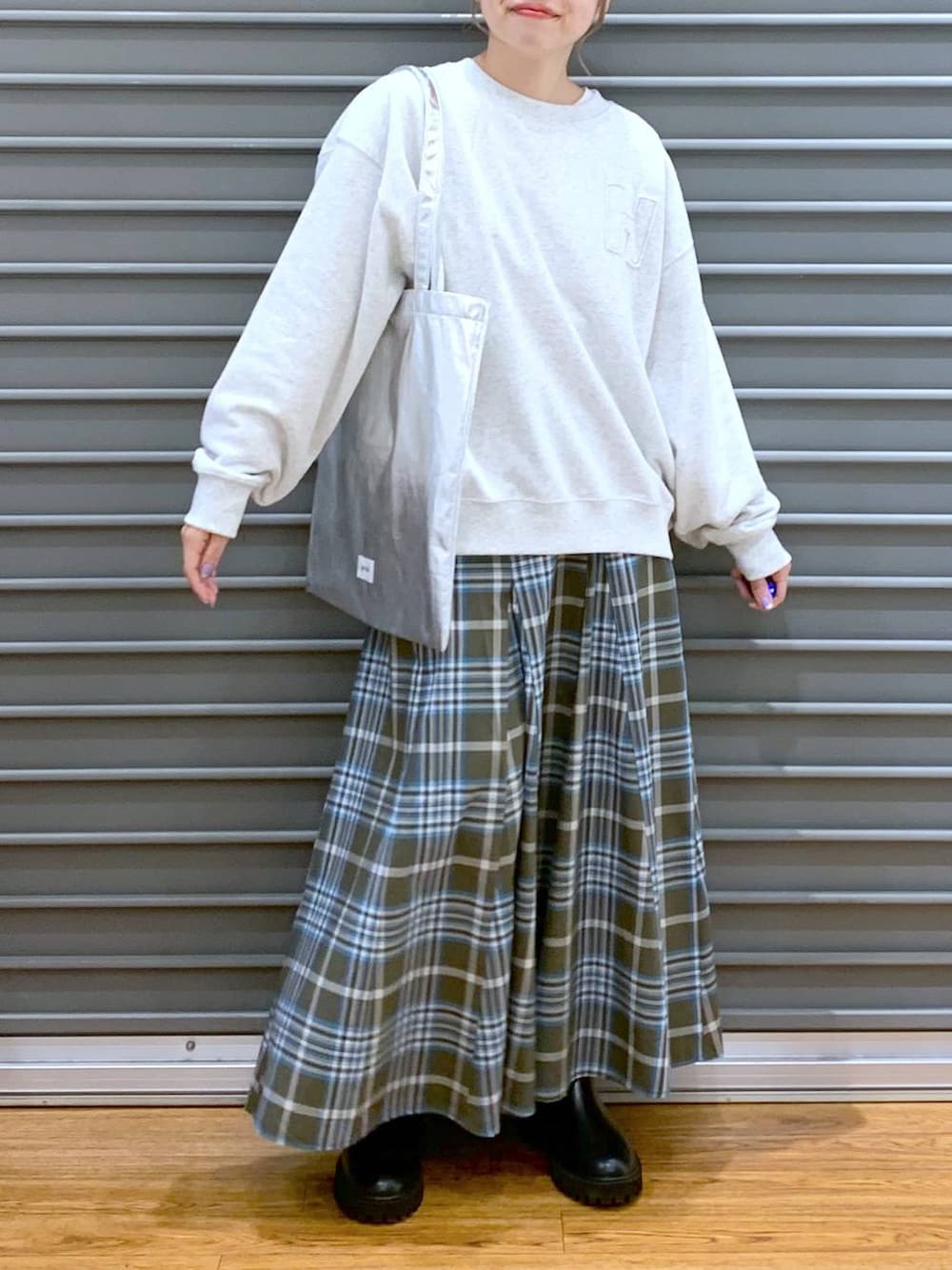 シルバー系のトートバッグ、ブラック系のブーツ、グリーン系のスカートを着用したレディースの冬コーディネートの8枚目の写真