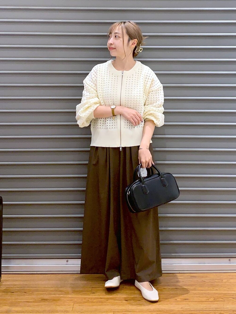 ブラウン系のスラックス、ホワイト系のパンプス、ブラック系のボストンバッグを着用したレディースの秋コーディネートの5枚目の写真