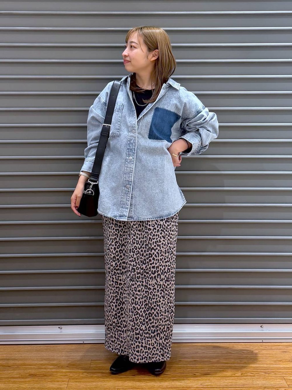 ブラック系のショルダーバッグ、ブルー系のシャツ/ブラウス、ブラック系のパンプスを着用したレディースの春コーディネートの6枚目の写真