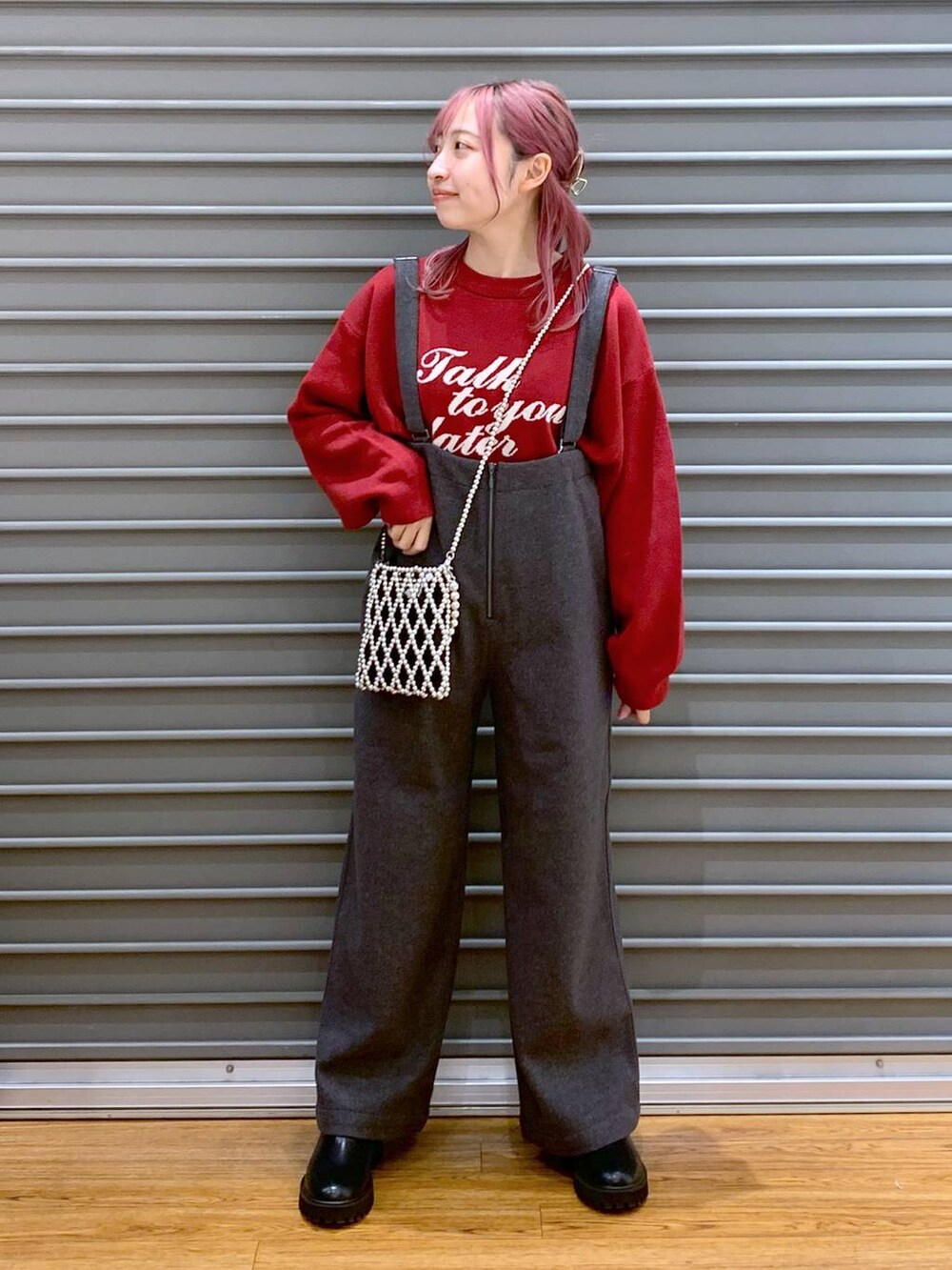 シルバー系のショルダーバッグ、レッド系のニット/セーター、ブラック系のブーツを着用したレディースの冬コーディネートの3枚目の写真