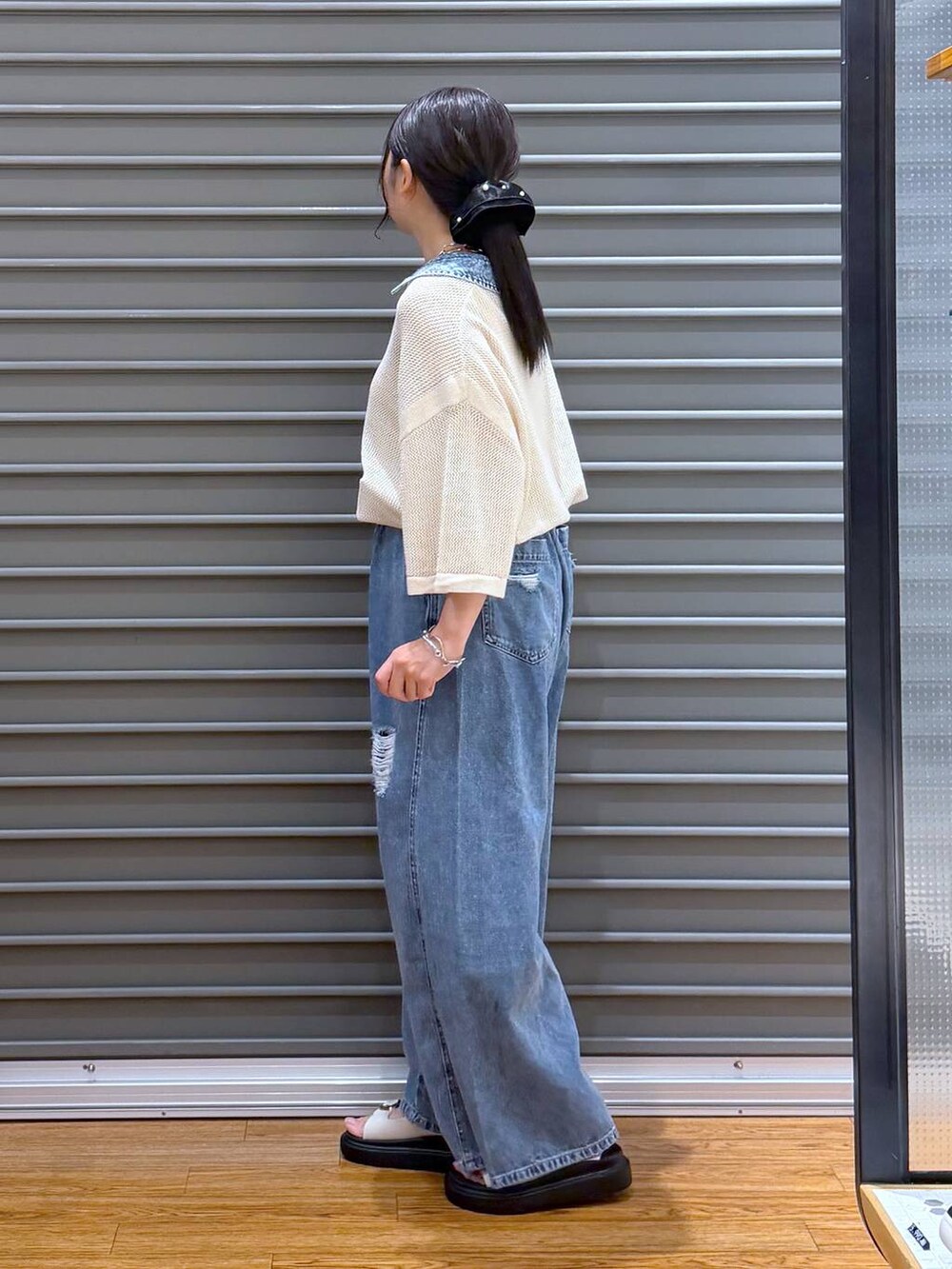 ブルー系のデニムパンツ、ホワイト系のサンダル、ブラック系のショルダーバッグを着用したレディースの夏コーディネートの3枚目の写真