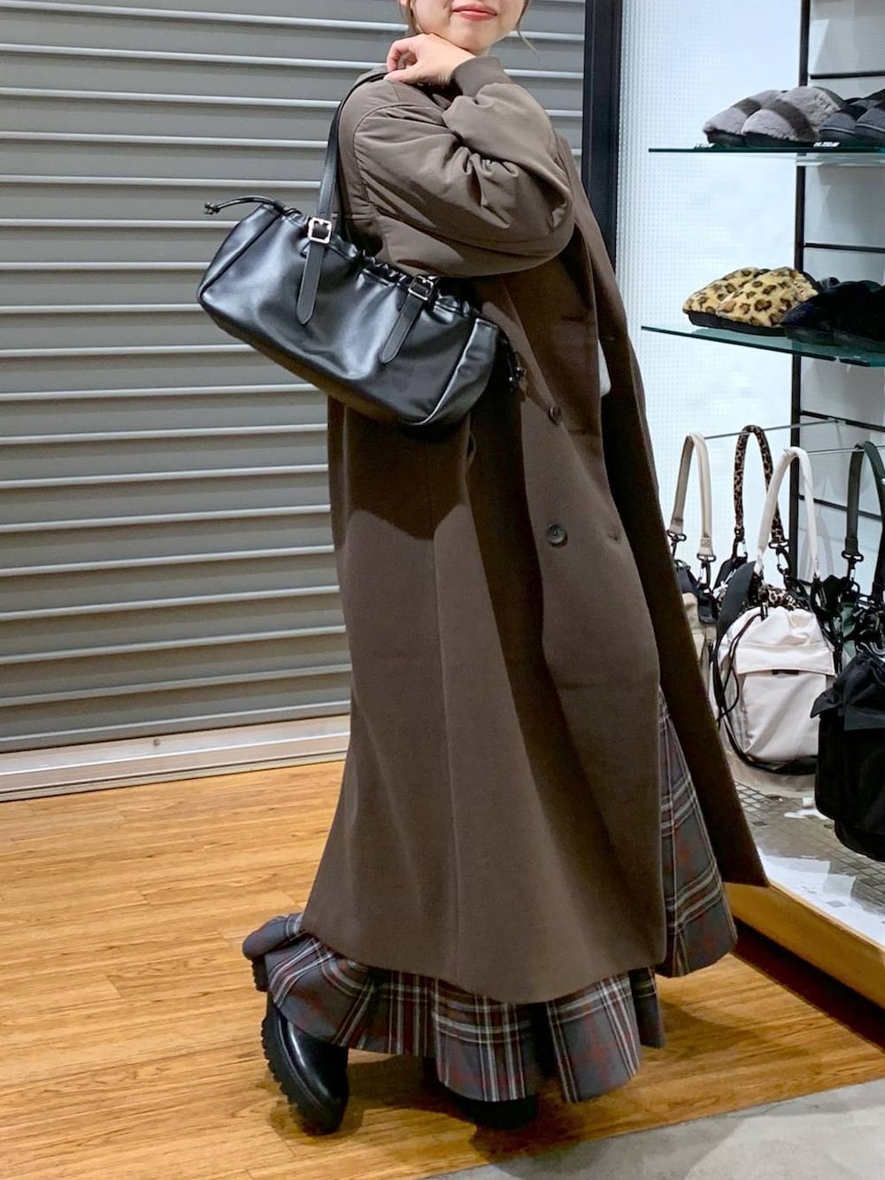 ブラック系のブーツ、グレー系のスカート、ブラック系のショルダーバッグを着用したレディースの冬コーディネートの4枚目の写真