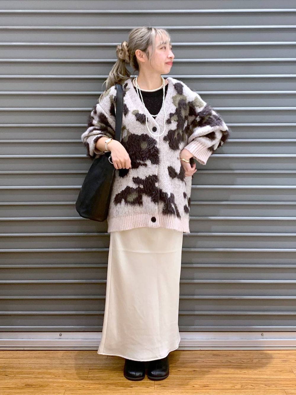 ホワイト系のスカート、ブラック系のショルダーバッグ、ブラック系のブーツを着用したレディースの冬コーディネートの4枚目の写真