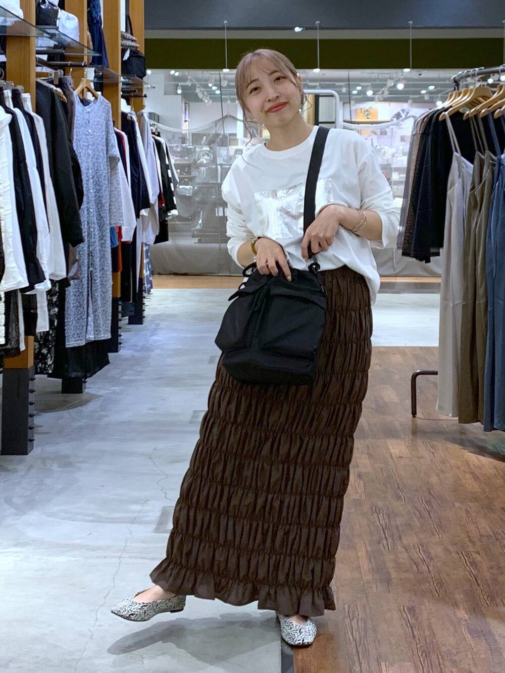 ブラック系のショルダーバッグ、ホワイト系のパンプス、イエロー系のスカートを着用したレディースの秋コーディネートの6枚目の写真