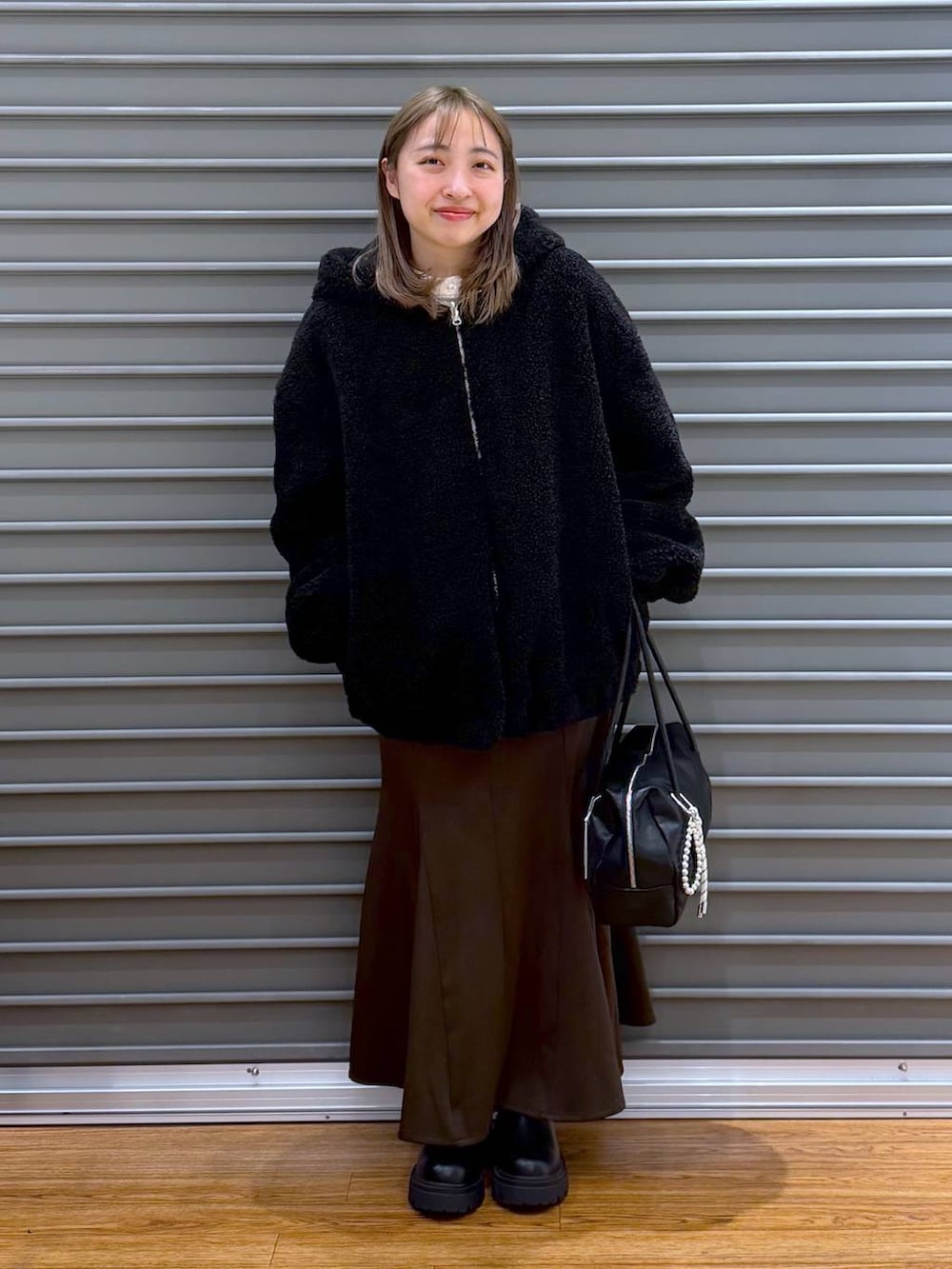 ブラック系のブーツ、ブラウン系のスカート、ブラック系のボストンバッグを着用したレディースの冬コーディネートの6枚目の写真