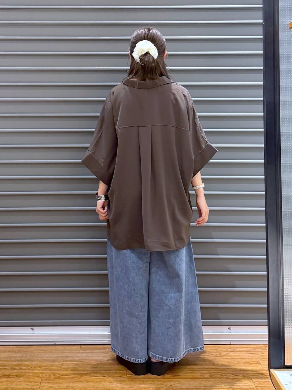 ブルー系のトートバッグ、ブラウン系のシャツ/ブラウス、ブラック系のサンダルを着用したレディースの夏コーディネートの2枚目の写真
