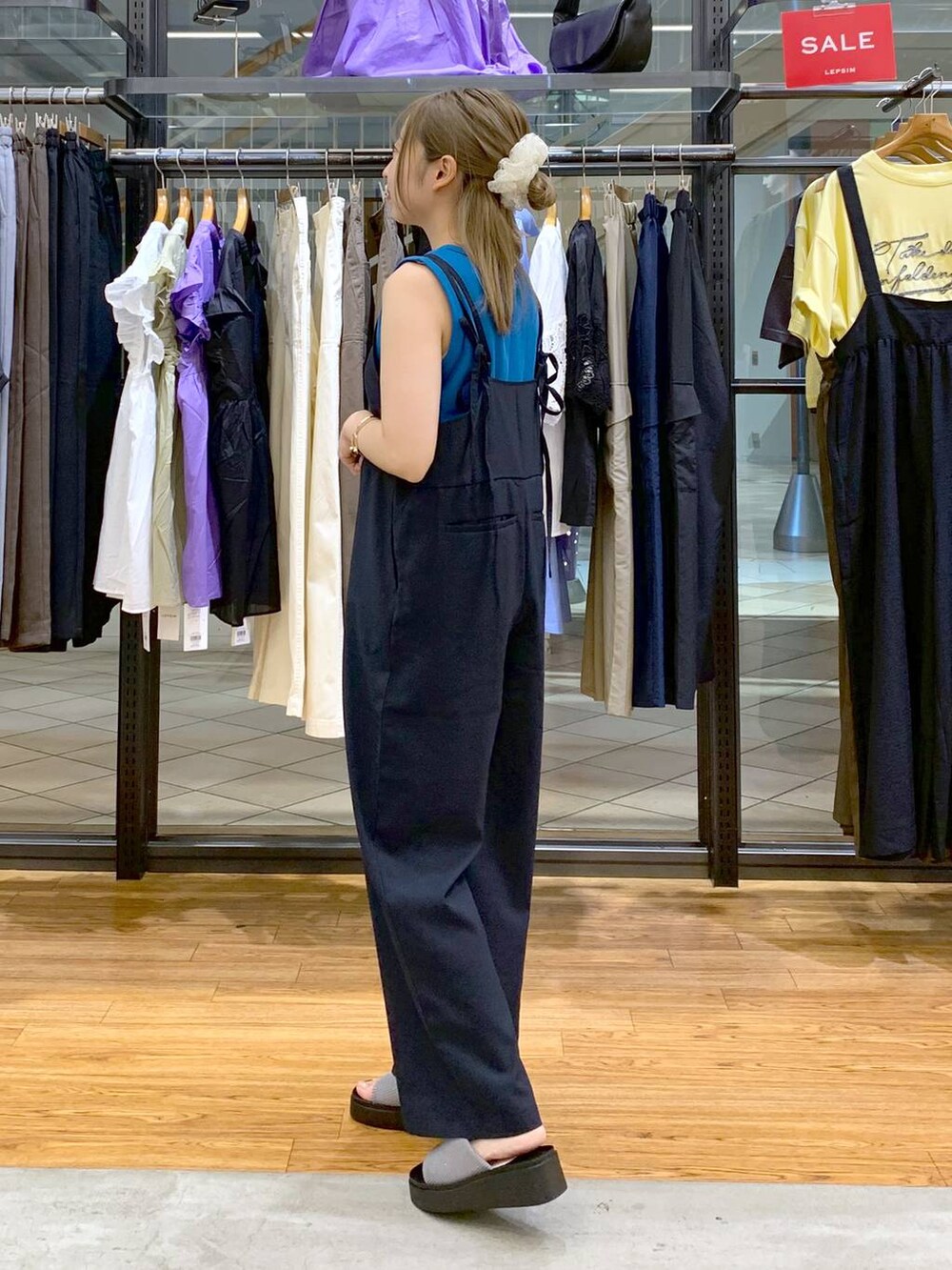 ブルー系のタンクトップ、シルバー系のサンダル、ブラック系のショルダーバッグを着用したレディースの秋コーディネートの3枚目の写真