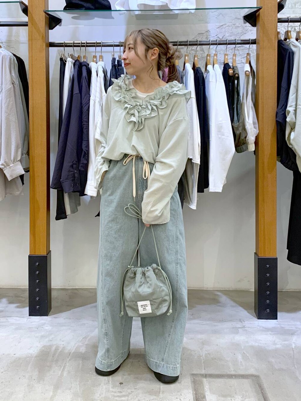 グリーン系のショルダーバッグ、ブルー系のデニムパンツ、ブラック系のサンダルを着用したレディースの春コーディネートの4枚目の写真