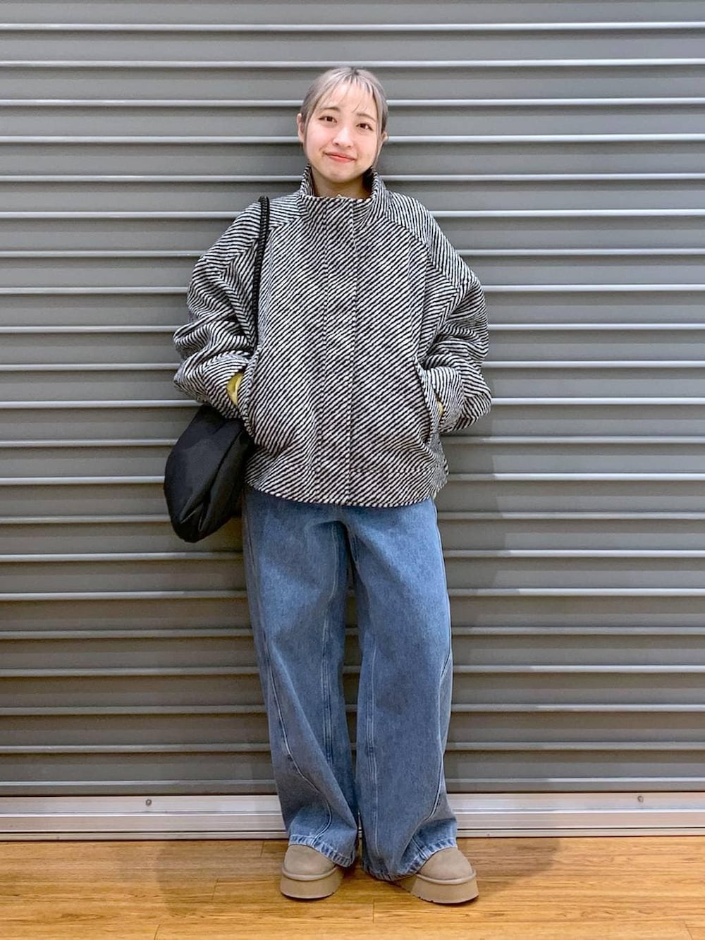 イエロー系のニット/セーター、ブラック系のブルゾン、ブラック系のトートバッグを着用したレディースの冬コーディネートの9枚目の写真