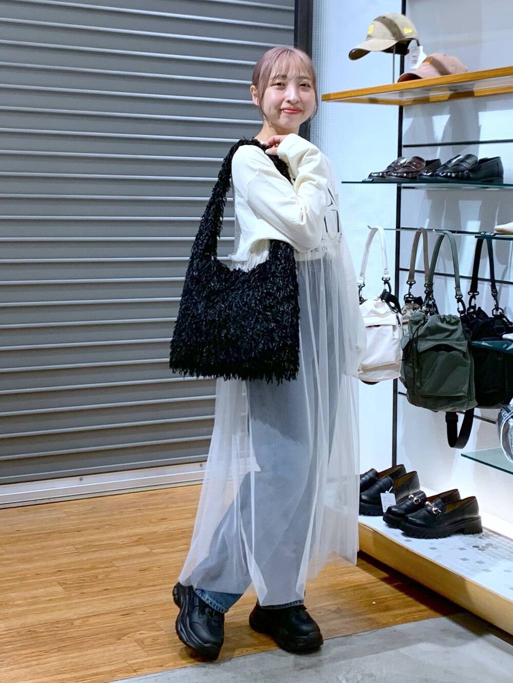 ブラック系のスニーカー、ブルー系のデニムパンツ、ブラック系のショルダーバッグを着用したレディースの秋コーディネートの7枚目の写真