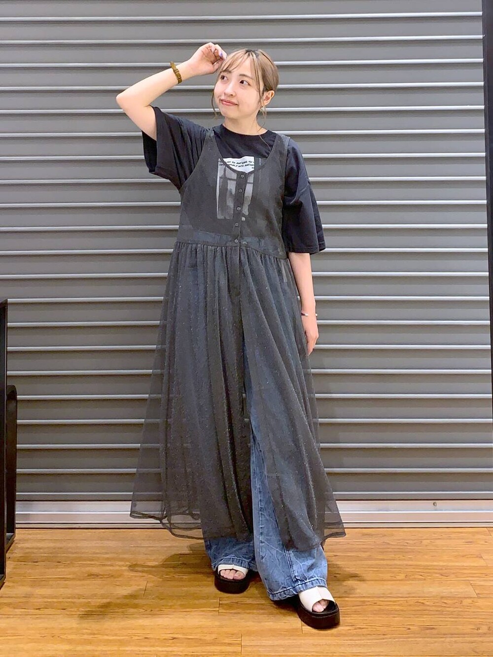 ブラック系のショルダーバッグ、ブルー系のデニムパンツ、ホワイト系のサンダルを着用したレディースの秋コーディネートの4枚目の写真