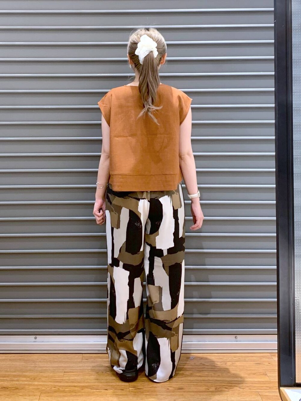 ブラック系のサンダル、オレンジ系のシャツ/ブラウス、ブラック系のショルダーバッグを着用したレディースの夏コーディネートの2枚目の写真