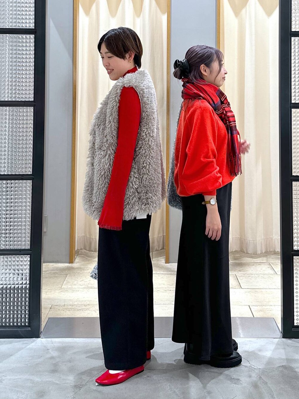 レッド系のニット/セーター、ブラック系のブーツ、シルバー系のショルダーバッグを着用したレディースの冬コーディネートの3枚目の写真