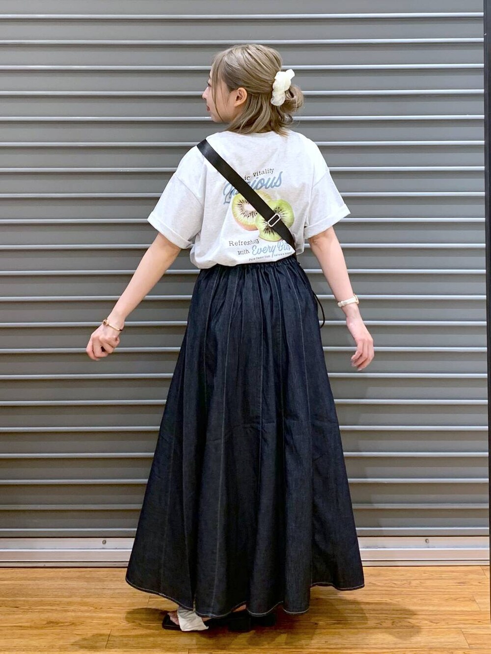 ブルー系のスカート、ホワイト系のサンダル、ブラック系のショルダーバッグを着用したレディースの夏コーディネートの3枚目の写真