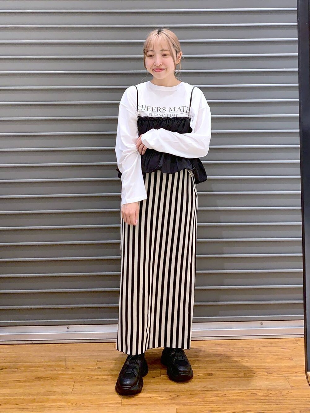 ブラック系のショルダーバッグ、ブラック系のスニーカー、ホワイト系のスカートを着用したレディースの春コーディネートの4枚目の写真