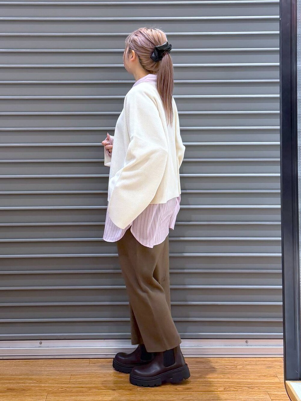 ブラウン系のスカート、ホワイト系のニット/セーター、ブラウン系のブーツを着用したレディースの冬コーディネートの3枚目の写真