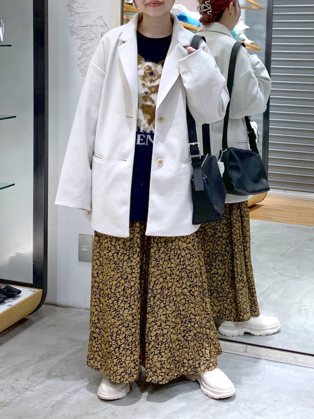 ホワイト系のその他アウター、ホワイト系のブーツ、ブラック系のショルダーバッグを着用したレディースの冬コーディネートの3枚目の写真