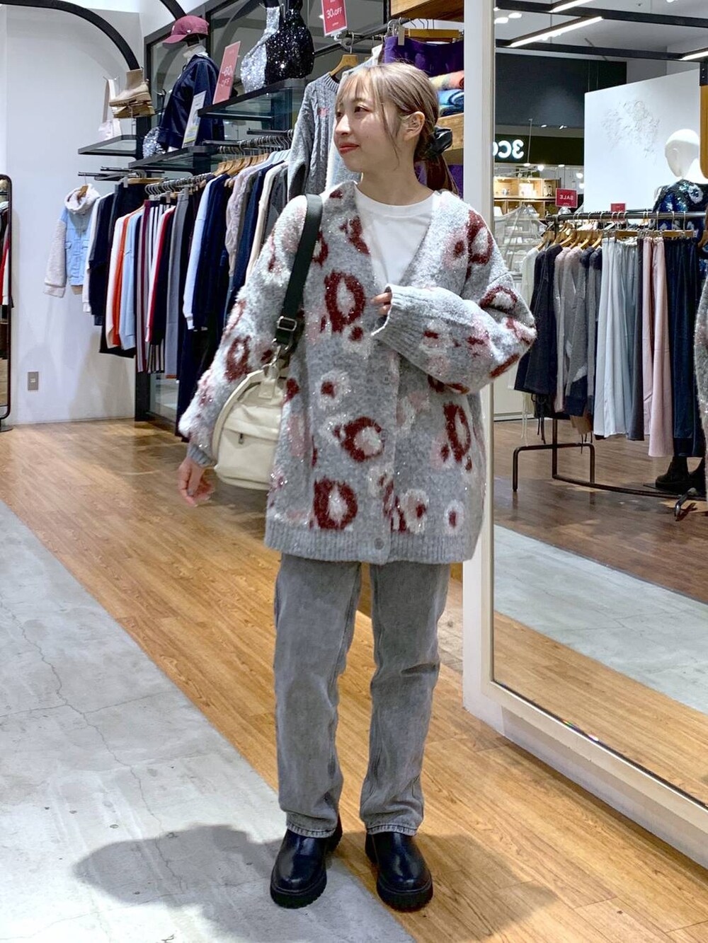 ブラック系のブーツ、グレー系のデニムパンツ、ホワイト系のショルダーバッグを着用したレディースの秋コーディネートの3枚目の写真