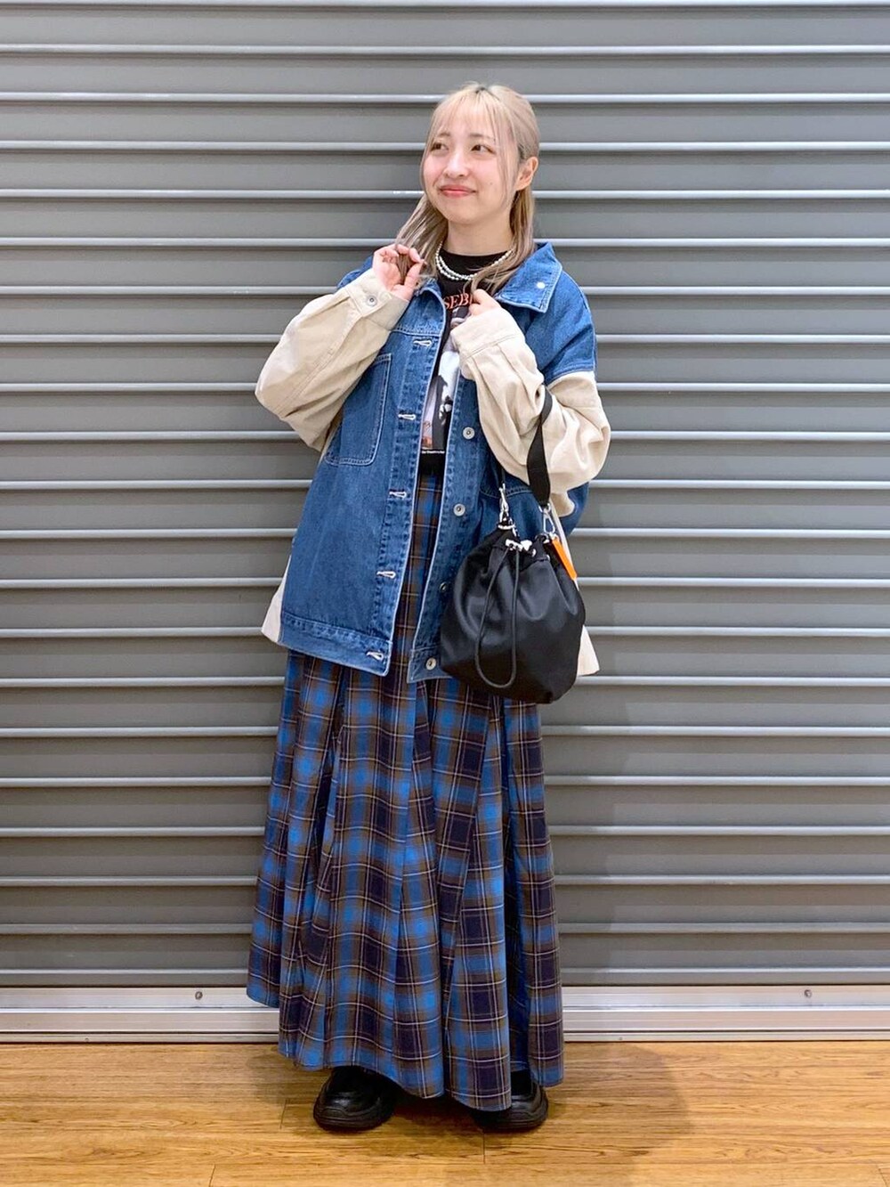 ブラック系のショルダーバッグ、ブラック系のスニーカー、ブルー系のカバーオールを着用したレディースの秋コーディネートの5枚目の写真