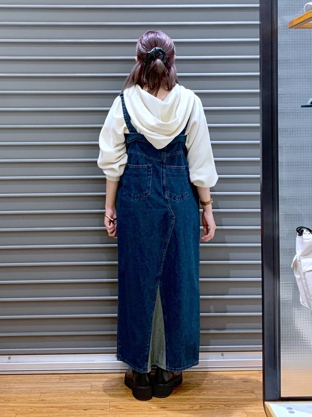 ホワイト系のショルダーバッグ、ブルー系のジャンパースカート、ブラック系のブーツを着用したレディースの冬コーディネートの3枚目の写真