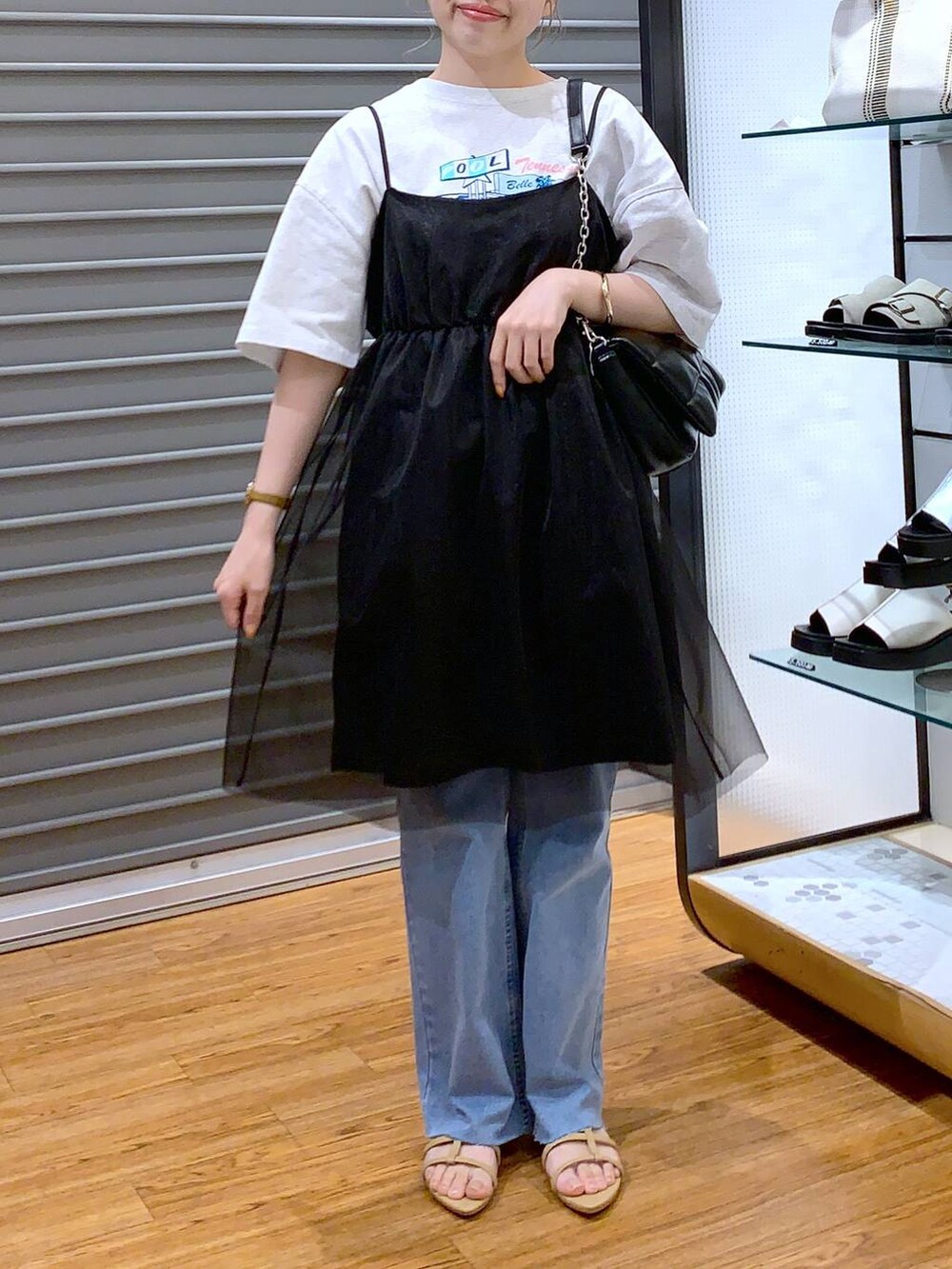 ブラック系のショルダーバッグ、ベージュ系のサンダル、ブルー系のデニムパンツを着用したレディースの夏コーディネートの3枚目の写真