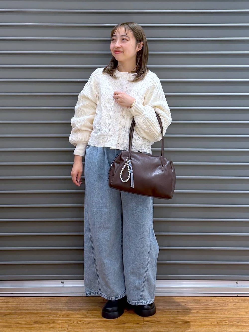 ブラック系のサンダル、ブルー系のデニムパンツ、ブラウン系のボストンバッグを着用したレディースの春コーディネートの5枚目の写真