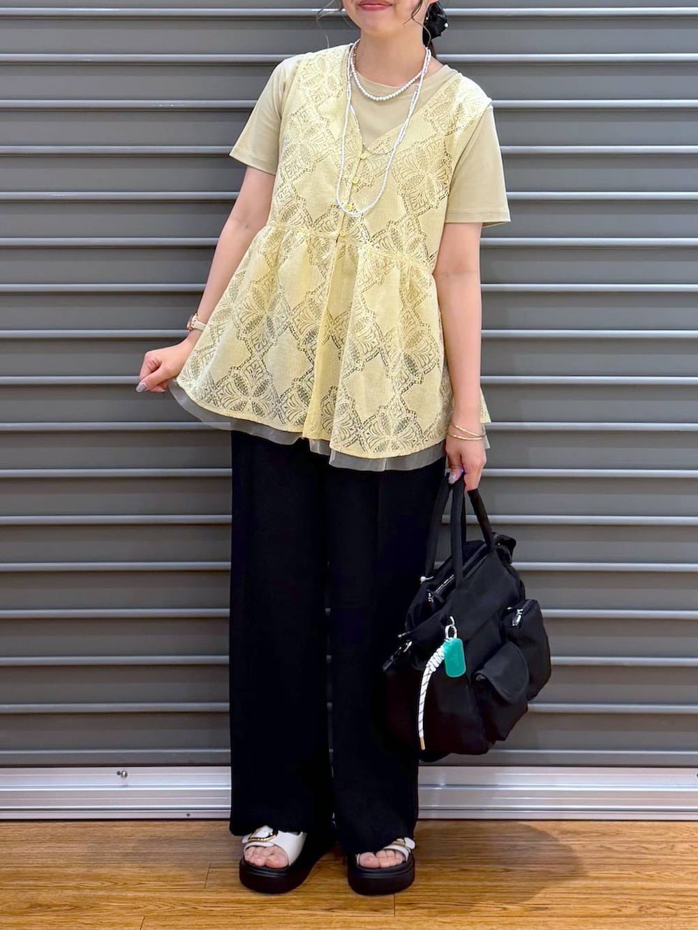 ブラック系のトートバッグ、ホワイト系のサンダル、ベージュ系のTシャツ/カットソーを着用したレディースの夏コーディネートの4枚目の写真