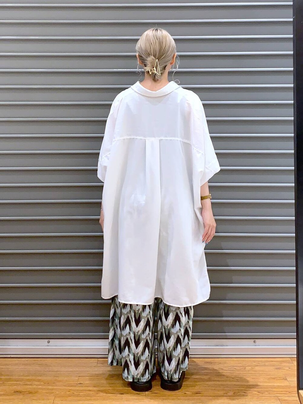 シルバー系のサンダル、ベージュ系のショルダーバッグ、ホワイト系のチュニックを着用したレディースの夏コーディネートの2枚目の写真